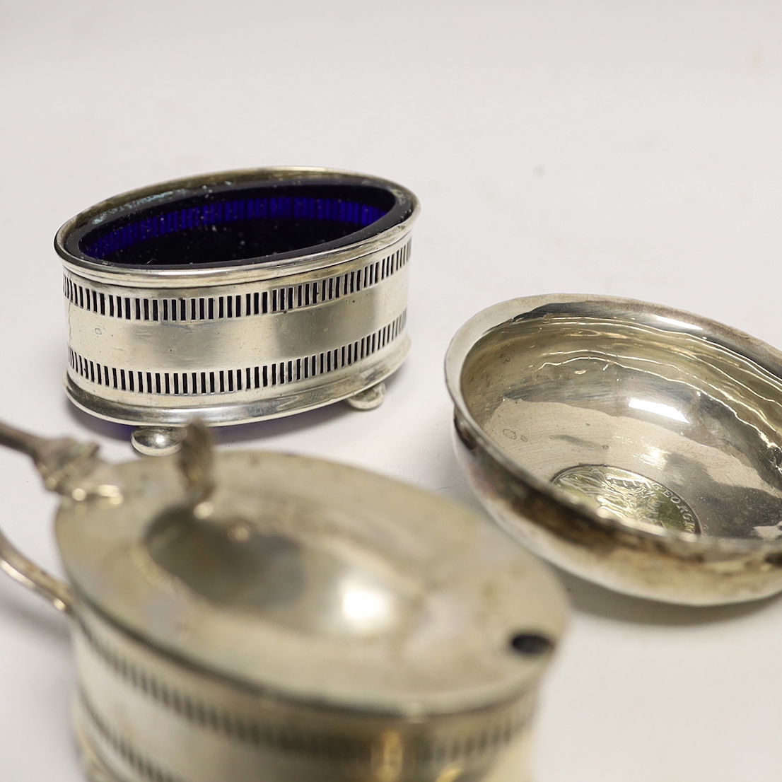 A 1930's silver single handled cup, a four piece silver condiment set, Edwardian silver card case, pair of silver pepperettes, napkin rings, sundry small flatware including sterling etc.